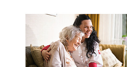 Eine Pflegefachkraft umarmt eine Seniorin herzlich